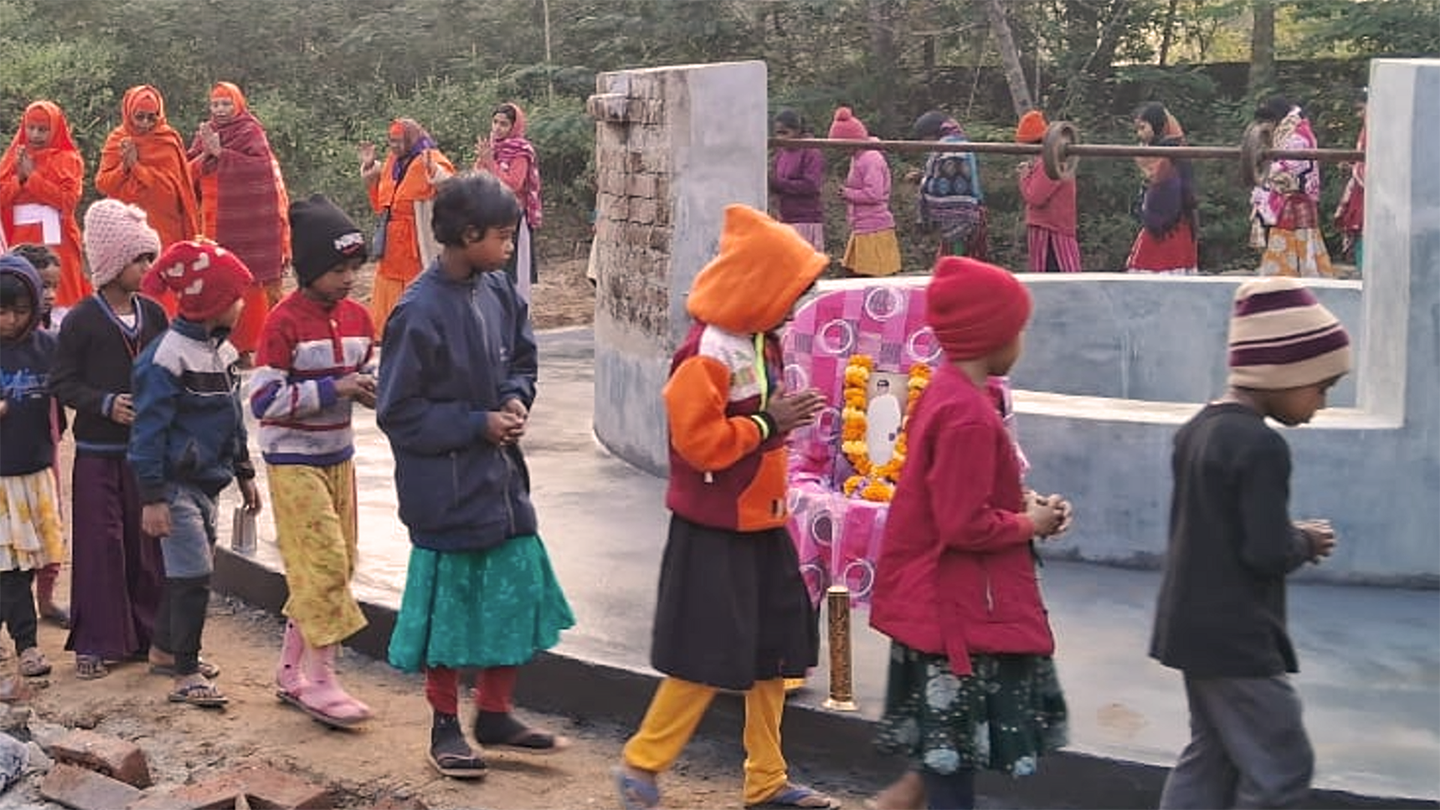 bambini e monache fanno kiirtan intorno al nuovo pozzo