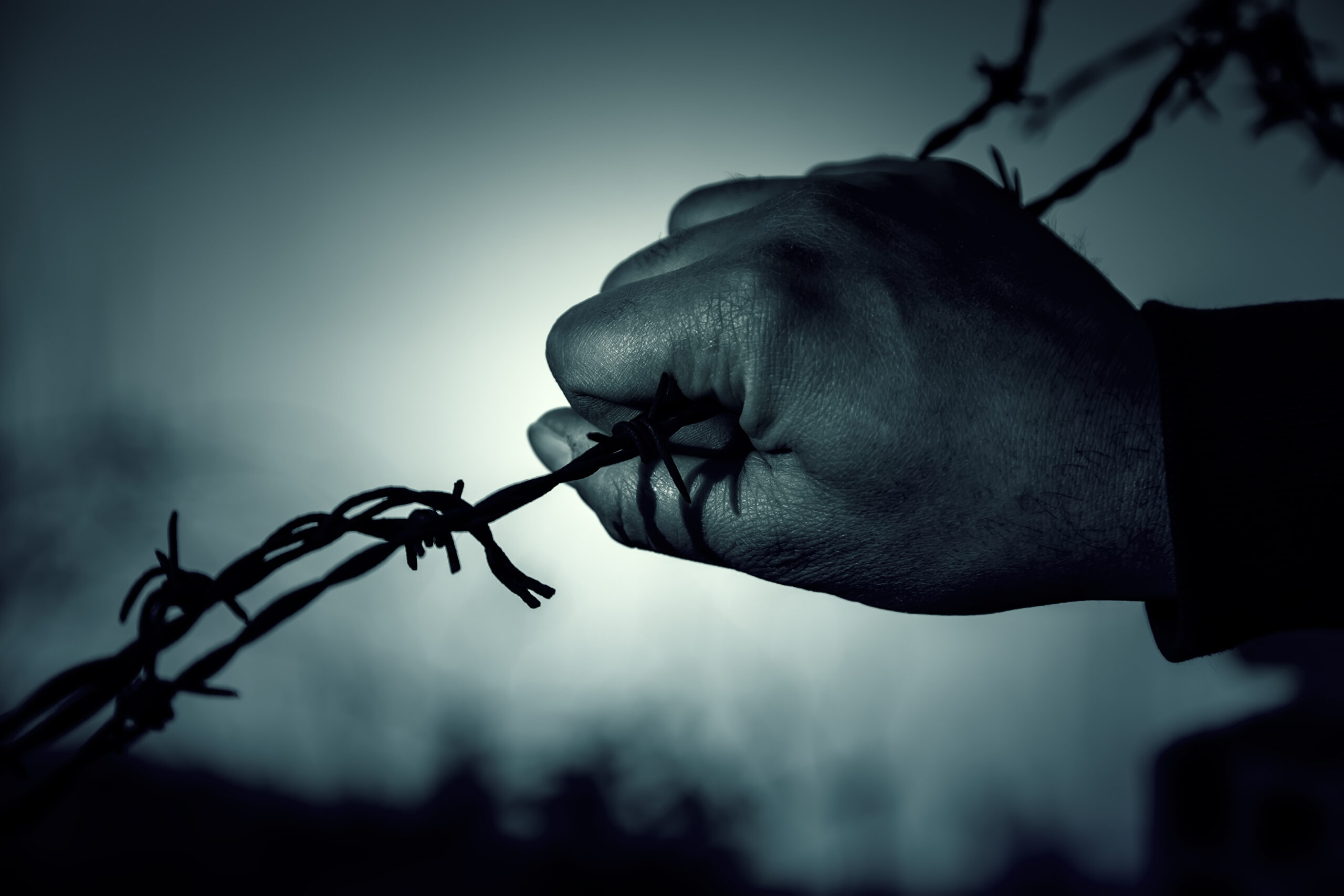 una mano stringe un filo spinato